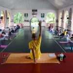 Group yoga session at Sivananda Ashram, featuring participants practicing yoga poses in a serene and spiritual environment, emphasizing mindfulness and inner peace