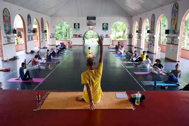 Group yoga session at Sivananda Ashram, featuring participants practicing yoga poses in a serene and spiritual environment, emphasizing mindfulness and inner peace