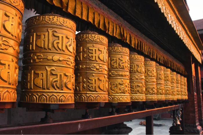 Close-up of prayer wheels in Kathmandu, Nepal, featuring intricate Tibetan script, a symbol of spirituality and Buddhist tradition.