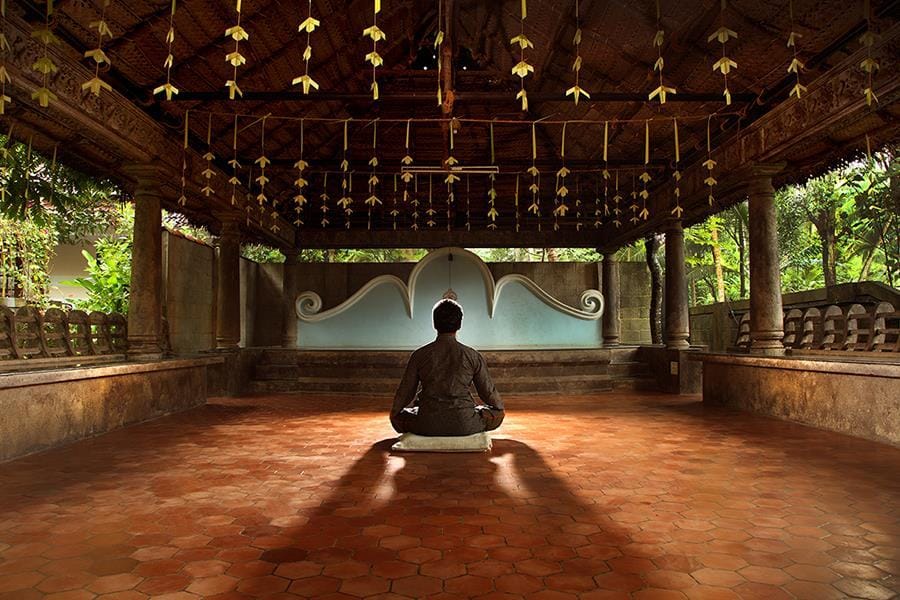 A serene image of a man meditating at Sivananda Ashram, Kerala, India, surrounded by tranquility and nature, embodying spiritual focus and mindfulness