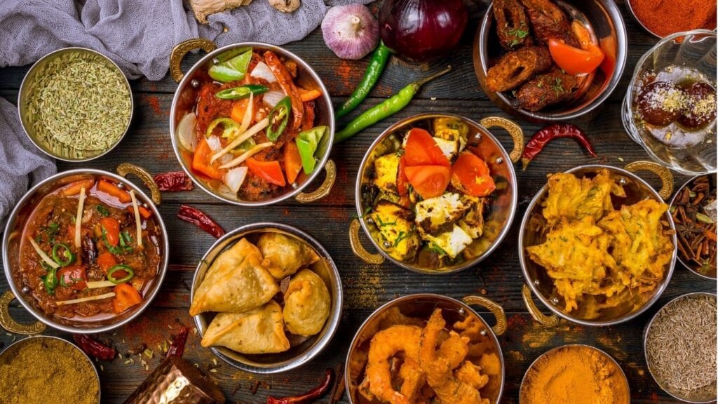 Table filled with a variety of delicious Indian dishes, featuring colorful curries, aromatic biryanis, naan bread, and vibrant chutneys, showcasing the richness of Indian cuisine