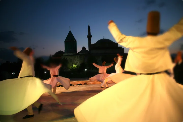 Konya, Türkiye 3 Whirling dervishes of the Mevlevi order performing the mesmerizing Sema dance in the courtyard of Rumi’s mausoleum under the night sky, with the ambiance enriched by soft illumination and the echo of spiritual music