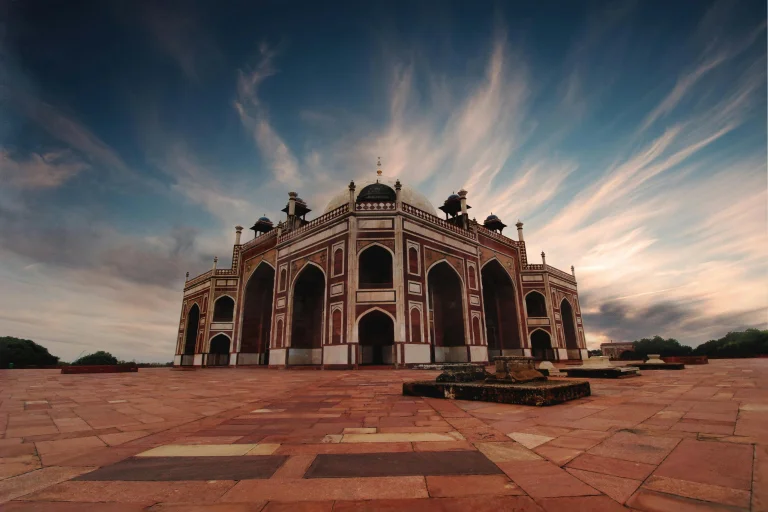 Delhi, India 3 Humayun's Tomb in Delhi under a clear blue sky, showcasing its stunning Mughal architecture with domes, arches, and beautifully manicured gardens