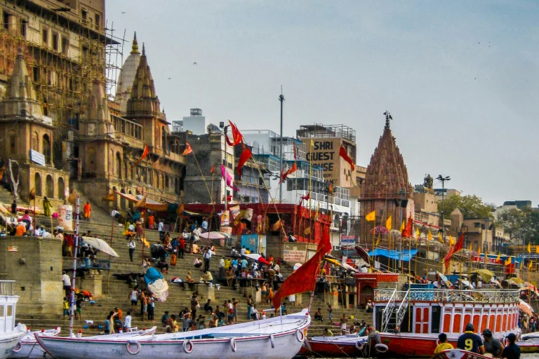 Varanasi, India 3 Scenic view of a riverside ghat in Varanasi along the Ganges River, bustling with spiritual activity, vibrant boats, and pilgrims performing sacred rituals under the golden hues of the evening sky